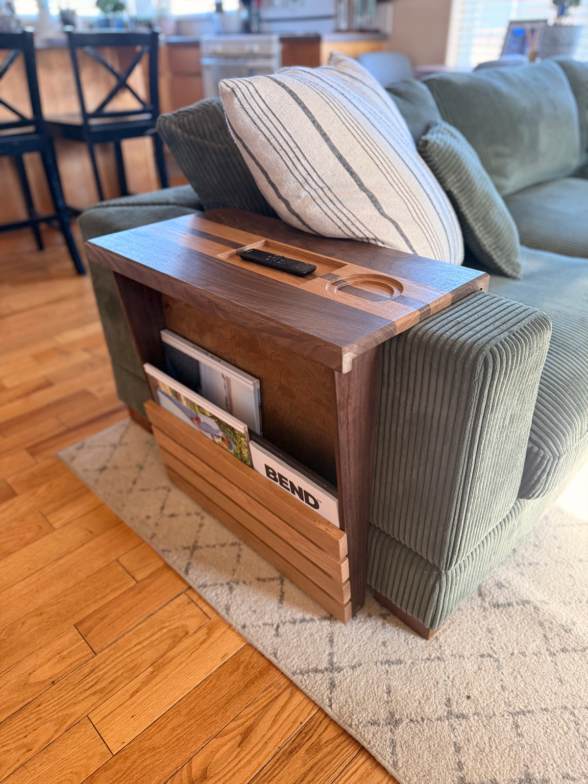 Wooden side table with cup holder and magazine rack on a green sofa